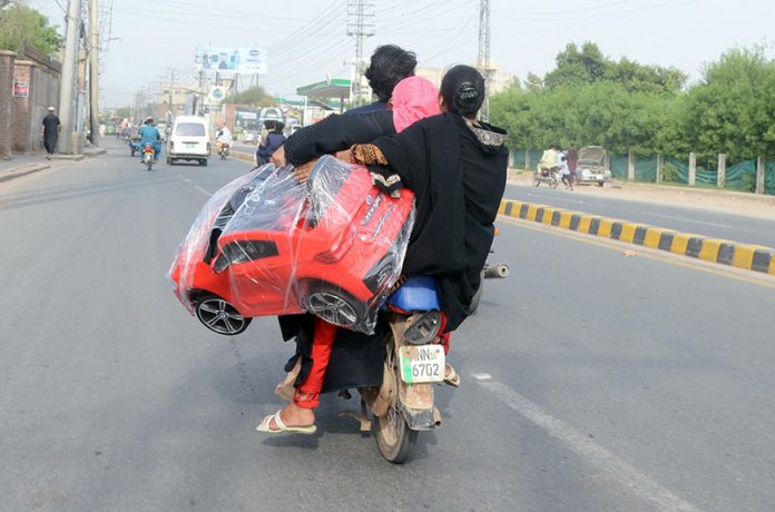 Woman holding a toy car while sitting rear seat of a Motorcycle