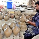 A craftsman busy in preparing clay made pots at his workplace.