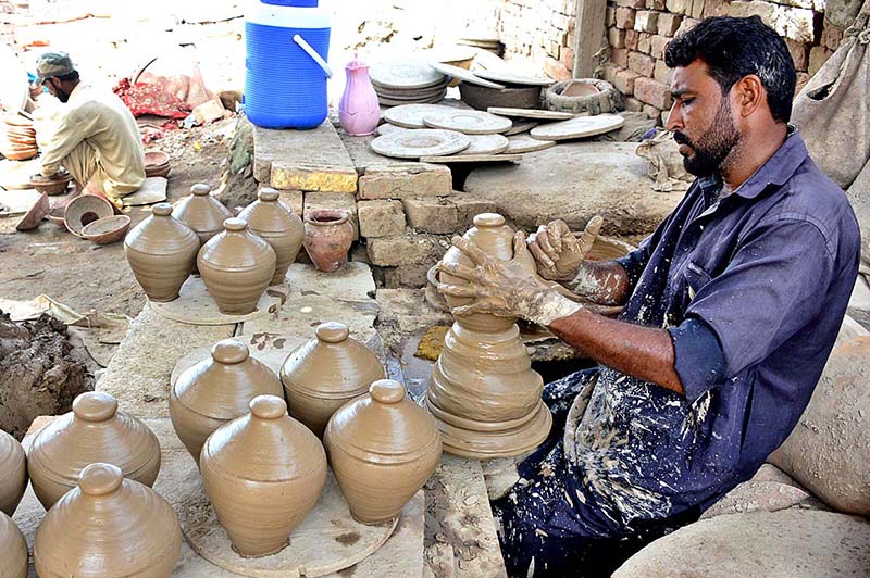 A craftsman busy in preparing clay made pots at his workplace.