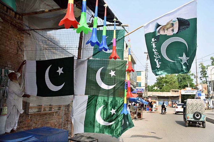 A vendor displaying national flags to attract the customers at his roadside setup in connection with upcoming Independence Day celebrations