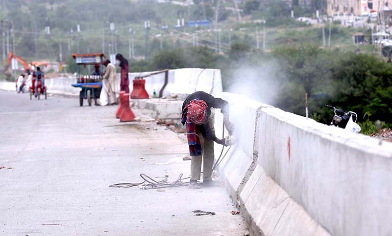 A worker busy in finishing work of road dividers during construction work on Islamabad Expressway