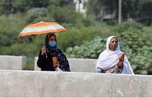 A woman on the way under cover of an umbrella to protect from direct sunlight during hot and humid weather at Pirwadai