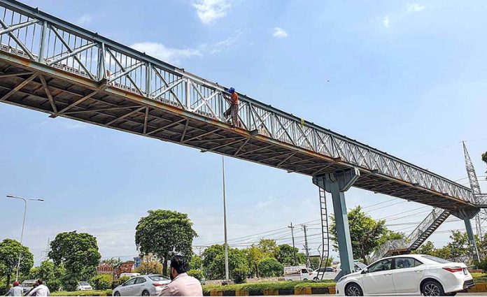 Workers busy in paint the overhead pedestrian bridge at Islamabad Expressway Workers busy in paint the overhead pedestrian bridge at Islamabad Expressway