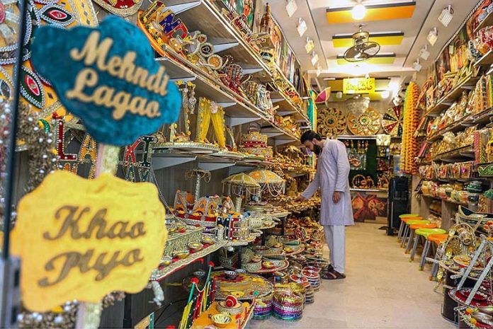 A shopkeeper arranging and displaying “Mehndi” related items to attract the customers in a local market