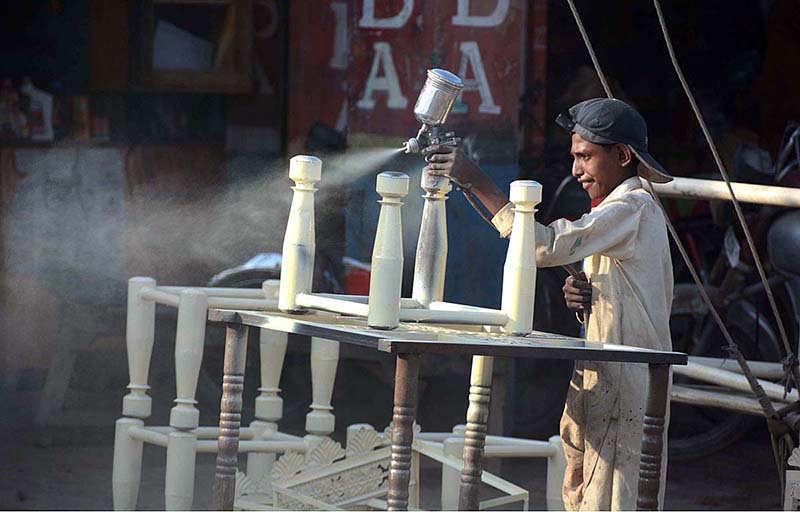 A young painter busy in painting iron frame at his workplace