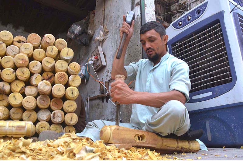 A carpenter busy in making part of a traditional bed (charpai) at his workplace in Dabgari area