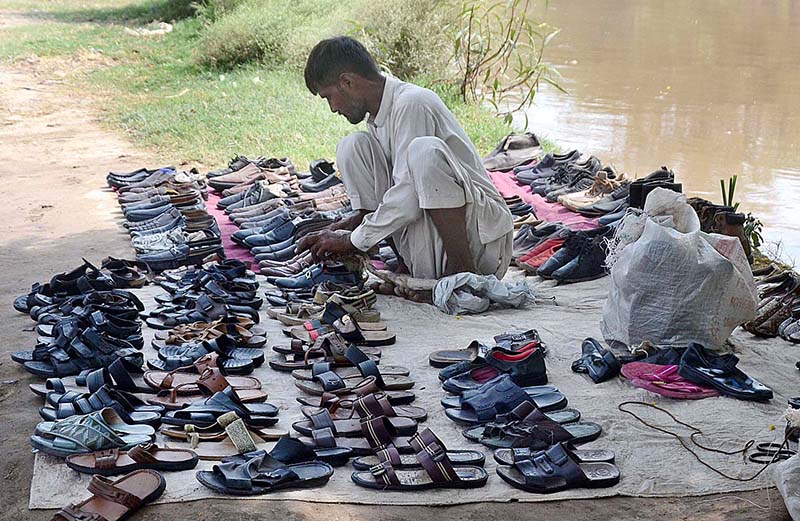 Vendor displaying old footwear to attract customers at Bank of Canal