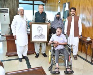 President Dr Arif Alvi receiving his portrait made by Mr Umer Jarral, an artist with cerebral palsy, at Aiwan-e-Sadr