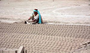 A woman labourer busy in preparing bricks at local bricks kiln