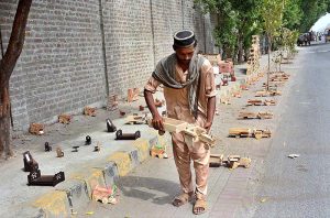 A vendor is displaying handmade wooden toys to attract the customers at his roadside setup