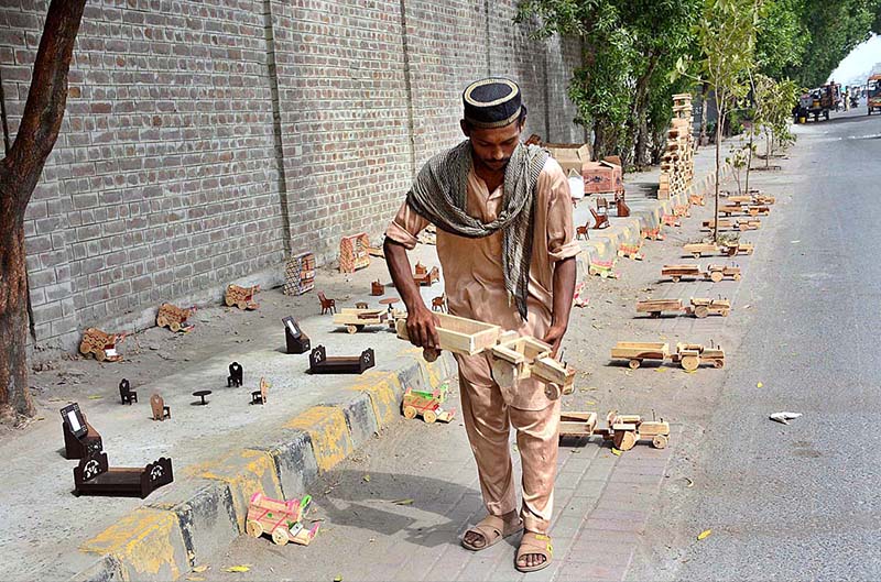 A vendor is displaying handmade wooden toys to attract the customers at his roadside setup A vendor is displaying handmade wooden toys to attract the customers at his roadside setup