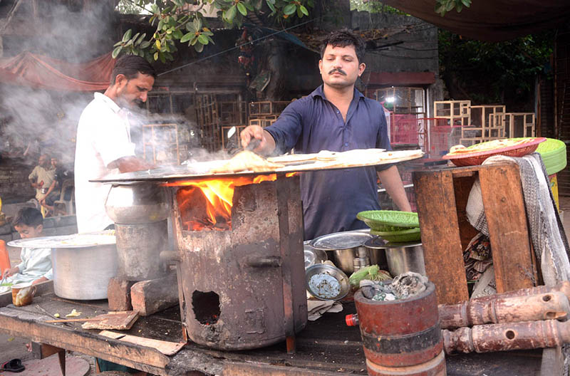 Vendor busy in preparing bread (Paratha) for customer at his roadside setup