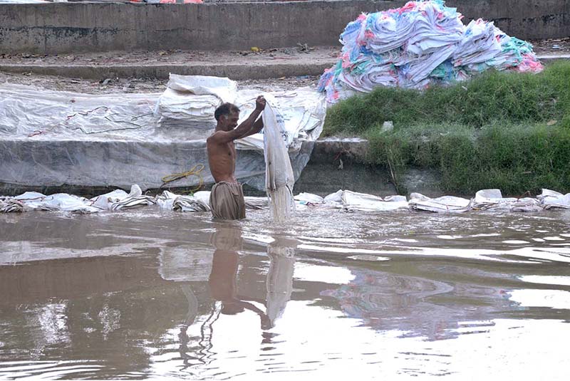 A vendor washing plastic sacks in local canal for reuse