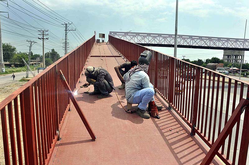 Workers busy in paint the overhead pedestrian bridge at Islamabad Expressway