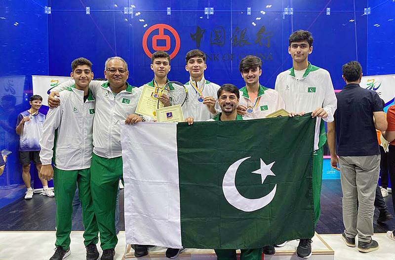 Squash players and coach in a group photograph with Pakistani Flag after winning Asian Junior Individual Squash Championship
