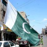 Vendor displaying big size national flag to attract the customer’s in preparation of upcoming Independence Day celebration of Pakistan