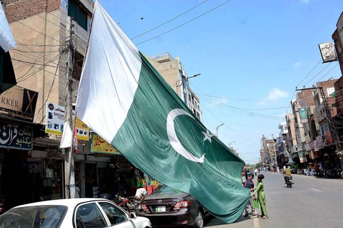 Vendor displaying big size national flag to attract the customer’s in preparation of upcoming Independence Day celebration of Pakistan Vendor displaying big size national flag to attract the customer’s in preparation of upcoming Independence Day celebration of Pakistan