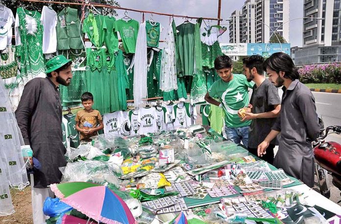 Youngsters busy in selecting and purchasing National flag and related stuff from vendor in connection with Pakistan Independence Day celebrations