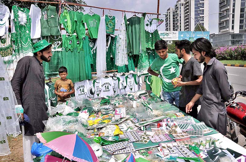 Youngsters busy in selecting and purchasing National flag and related stuff from vendor in connection with Pakistan Independence Day celebrations