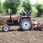 Farmers busy in ploughing his field with the help of tractor for next crop