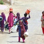 Gypsy girls on the way while carrying water canes for filling clean water at Qasimabad