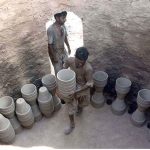 Labourers placing clay made flower pots in a huge traditional mud oven