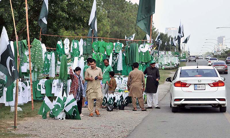 Youngsters busy in selecting and purchasing National flag and related stuff from vendor in connection with Pakistan Independence Day celebrations