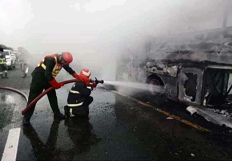 RESCUE 1122 officials extinguishing fire on bus after incidence while eighteen people were killed and fifteen others injured when a passenger bus caught fire after being smashed into a pick-up carrying diesel drums at Motorway near Pindi Bhattian