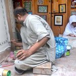 A skilled individual is engaged in embroidery work on a bed sheet and pillow at Walled City