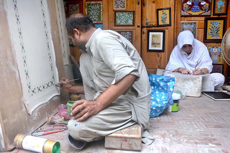 A skilled individual is engaged in embroidery work on a bed sheet and pillow at Walled City