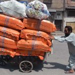 Laborer struggling to push his handcart loaded with domestic item at Yakatoot area