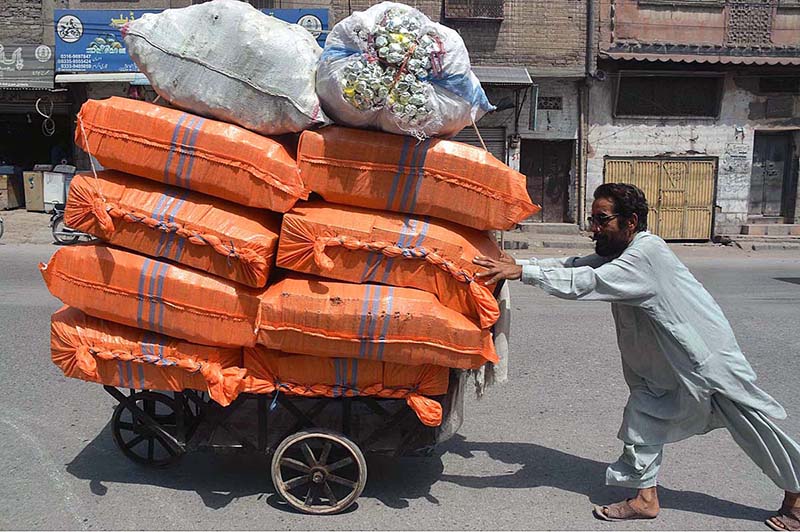 Laborer struggling to push his handcart loaded with domestic item at Yakatoot area