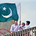 Students install national flag on the roof of private school at Latifabad in connection with Pakistan Independence Day celebrations