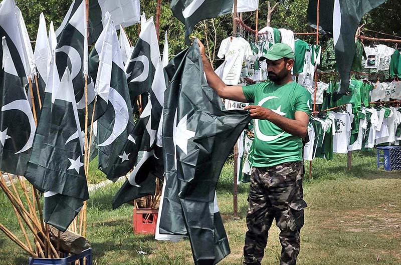 Youngsters busy in selecting and purchasing National flag and related stuff from vendor in connection with Pakistan Independence Day celebrations