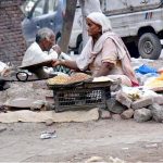 An elderly lady is cooking corn kernels near the Shahi Qila