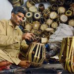 An artisan busy in repairing musical instrument (drums) at his workplace in the Kohati area