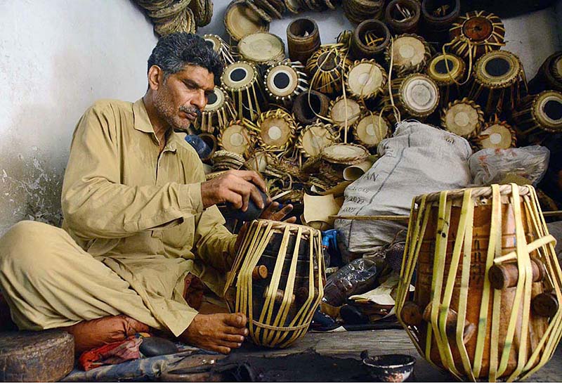 An artisan busy in repairing musical instrument (drums) at his workplace in the Kohati area