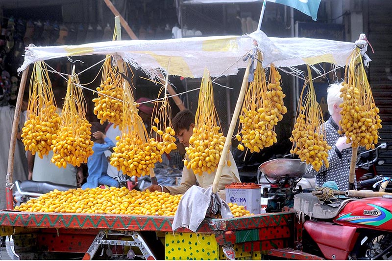 A vendor displaying and selling fresh dates at his roadside setup