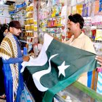 Family purchasing national flag in preparation of upcoming Independence Day celebration of Pakistan