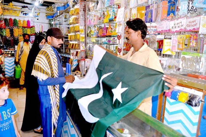 Family purchasing national flag in preparation of upcoming Independence Day celebration of Pakistan