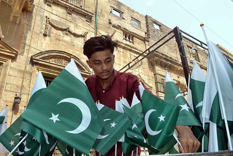 Students install national flag on the roof of private school at Latifabad in connection with Pakistan Independence Day celebrations