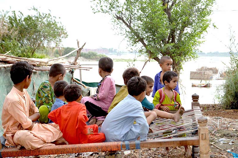 Children sitting on traditional bad (charpai) at kacha area near Indus river