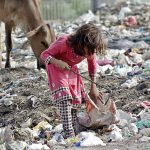 Gypsy girl searching valuables from the heap of garbage