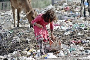 Gypsy girl searching valuables from the heap of garbage