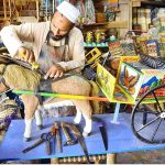 An artisan gives the final touch to a wooden horse cart (Tanga) for decoration at his workplace