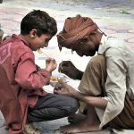 Gypsy person along with his son eating potato chips at Abpara Market