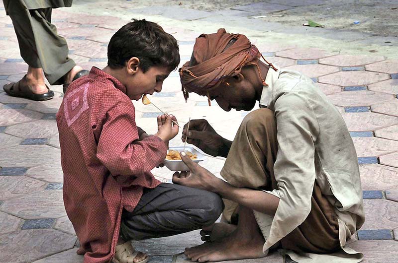 Gypsy person along with his son eating potato chips at Abpara Market