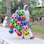 A woman selling football while shuttling in the park