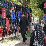 A woman along with her children busy in selecting and purchasing school bags from vendor at Sunday Bazaar in Federal Capital.