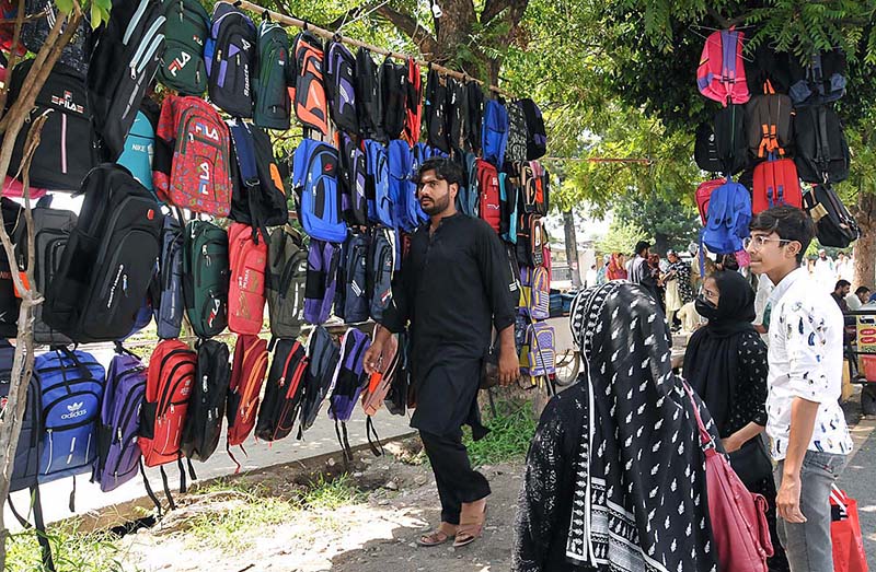 A woman along with her children busy in selecting and purchasing school bags from vendor at Sunday Bazaar in Federal Capital.